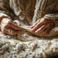 Close-up image of elderly hands skillfully knitting a textured cable-knit sweater Royalty Free Stock Photo