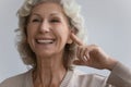 Elderly woman points finger to ear with hearing aid device Royalty Free Stock Photo