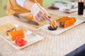 Close-up image of female hand in glove holding a sushi roll in chopsticks dipping it in soy sauce in kitchen Royalty Free Stock Photo