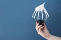 Close up image of female hand holds a metallic whisk with white protein cream on a blue background.