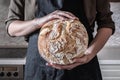 Close-up image of female hands holding big loaf of white bread.