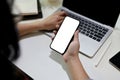 Close-up image of a female offie worker using her smartphone while using laptop at her desk Royalty Free Stock Photo