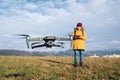 Close up image of flying drone with Teenager boy dressed yellow jacket on background piloting a modern digital drone using remote