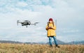 Close up image of flying drone with Teenager boy dressed yellow jacket on background piloting a modern digital drone using remote