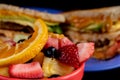 A close up image of fruit with a hearty breakfast sandwich