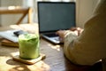 Close-up image of a glass of iced matcha green tea on a wooden table in a minimal cafe Royalty Free Stock Photo