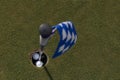 Closeup of a blue  flag in a golf cup with balls in a green golf course Royalty Free Stock Photo