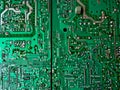 A close-up image of a green circuit board with various silver and gold components. Green computer circuit board as a background. Royalty Free Stock Photo
