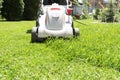 Close up image of grey electric lawn mower cutting green grass in garden. Royalty Free Stock Photo