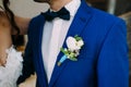 Close-up image of a groom in a blue tuxedo with White boutonniere. Boutonniere on the groom`s jacket. Artwork