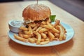 Close-up image of a hamburger with French fries and spicy sauce on a white plate. Unhealthy food concept Royalty Free Stock Photo