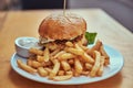 Close-up image of a hamburger with French fries and spicy sauce on a white plate. Unhealthy food concept Royalty Free Stock Photo