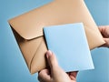 Hand holding brown envelope with white paper against blue background Royalty Free Stock Photo