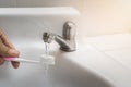 Close up image of a hand holding a pink toothbrush with Water being poured on toothpaste on top in bathroom sink Royalty Free Stock Photo