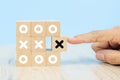 Close-up image of hand-picked cube shaped wooden toy blocks with X symbol stacked for business management and strategy Royalty Free Stock Photo