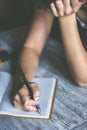 Close up of woman& x27;s hands writing in notepad placed on wooden desktop with various items