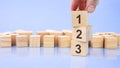 close up image hand of a young businessman holding a wooden cube with digit 1. 123 on wooden cube on a blue background Royalty Free Stock Photo