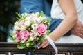 A close-up image of the hands of the bride and groom, holding each other and a bouquet of a beautiful white and pink flower pink. Royalty Free Stock Photo