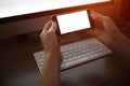 Close-up image of hands holding smartphone with blank mockup on background of keyboard Royalty Free Stock Photo