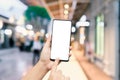 Close-up image of hands using smartphone in evening on city shopping street, Mockup blank white screen mobile phone with finger Royalty Free Stock Photo