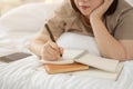 Close-up image of a happy Asian plus-size woman is keeping her diary on her bed at home Royalty Free Stock Photo