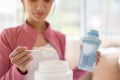 Close-up image of a healthy Asian woman in sportswear making her protein shake after a workout