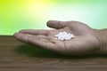 Close-up image of homeopathic pills in man`s hand on wooden table with green mix yellow background Royalty Free Stock Photo