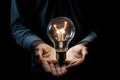 Close-up image of human hands holding incandescent light bulb, Conceptual image of a lightbulb in hand against a black background Royalty Free Stock Photo