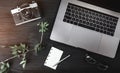 Close-up image of laptop, photo camera, eyeglasses, rose branch and white sheet on black wooden table Royalty Free Stock Photo