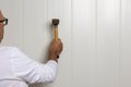 Close-up image of a male construction worker with a hammer skillfully tapping a nail into a wall Royalty Free Stock Photo