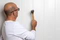 Close-up image of a male construction worker with a hammer skillfully tapping a nail into a wall Royalty Free Stock Photo