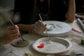 Close-up image of a man enjoying painting a ceramic plate in a creative handicraft workshop