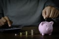 Close-up image of man hand putting coins in pink piggy bank for account save money. Royalty Free Stock Photo