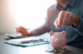 Close-up image of man hand putting coins in pink piggy bank for account save money. Royalty Free Stock Photo