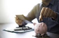 Close-up image of man hand putting coins in pink piggy bank for account save money. Royalty Free Stock Photo