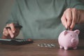 Close-up image of man hand putting coins in pink piggy bank for account save money. Royalty Free Stock Photo