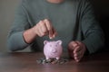 Close-up image of man hand putting coins in pink piggy bank for account save money. Royalty Free Stock Photo