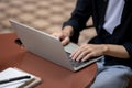 Close-up image of a man using his laptop computer, sitting at a table outdoors, working remotely Royalty Free Stock Photo