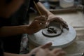 Close-up image of a man using a sculpting tool on raw clay on a pottery wheel at a table Royalty Free Stock Photo