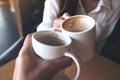 Close up image of a man and a woman clinking white coffee mug