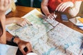 Close-up image of map lying on table and female hands pointing at it