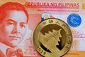 An orange 20 Phillippine peso bank note with a Chinese gold coin