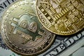 Close-up image of a pair of Bitcoins seen on top of a regular One Dollar Bill.