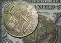Close-up image of a pair of Bitcoins seen on top of a regular One Dollar Bill.