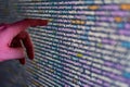 A close-up image of a hand pointing at a code display on a large screen, likely in a modern software development