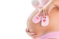 Close-up image of pregnant woman with pink babygirl shoes on her belly. Isolated background.