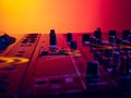 Close-up image of professional dj sound mixer isolated over gradient red yellow background in neon light