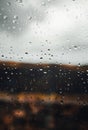 Close up image of raindrops on the window with cloudy sky on background. Vertical image of rain drops on the glass with outdoor on Royalty Free Stock Photo