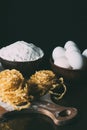 close up image of raw pasta, bowls, flour, eggs and cutting board