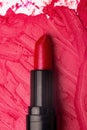 Close-up image of red lipstick on a smudged lipstick background